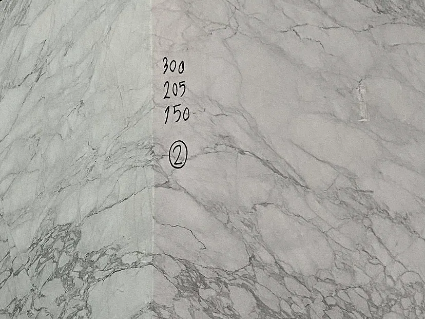 Photograph: a squared block of bright white stone with grey breccia-like veining at the quarry, hand-marked in black 300, 205 and 150 with a circled 2.