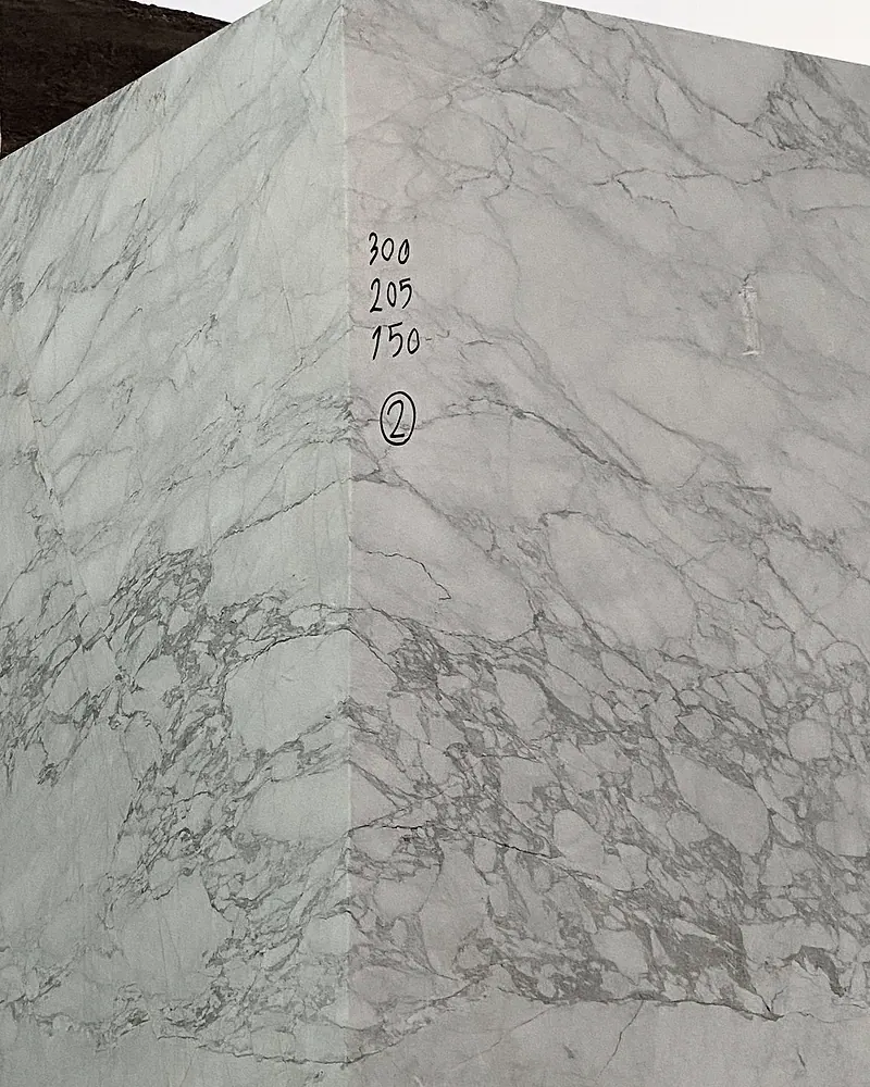 Photograph: a squared block of bright white stone with grey breccia-like veining at the quarry, hand-marked in black 300, 205 and 150 with a circled 2.