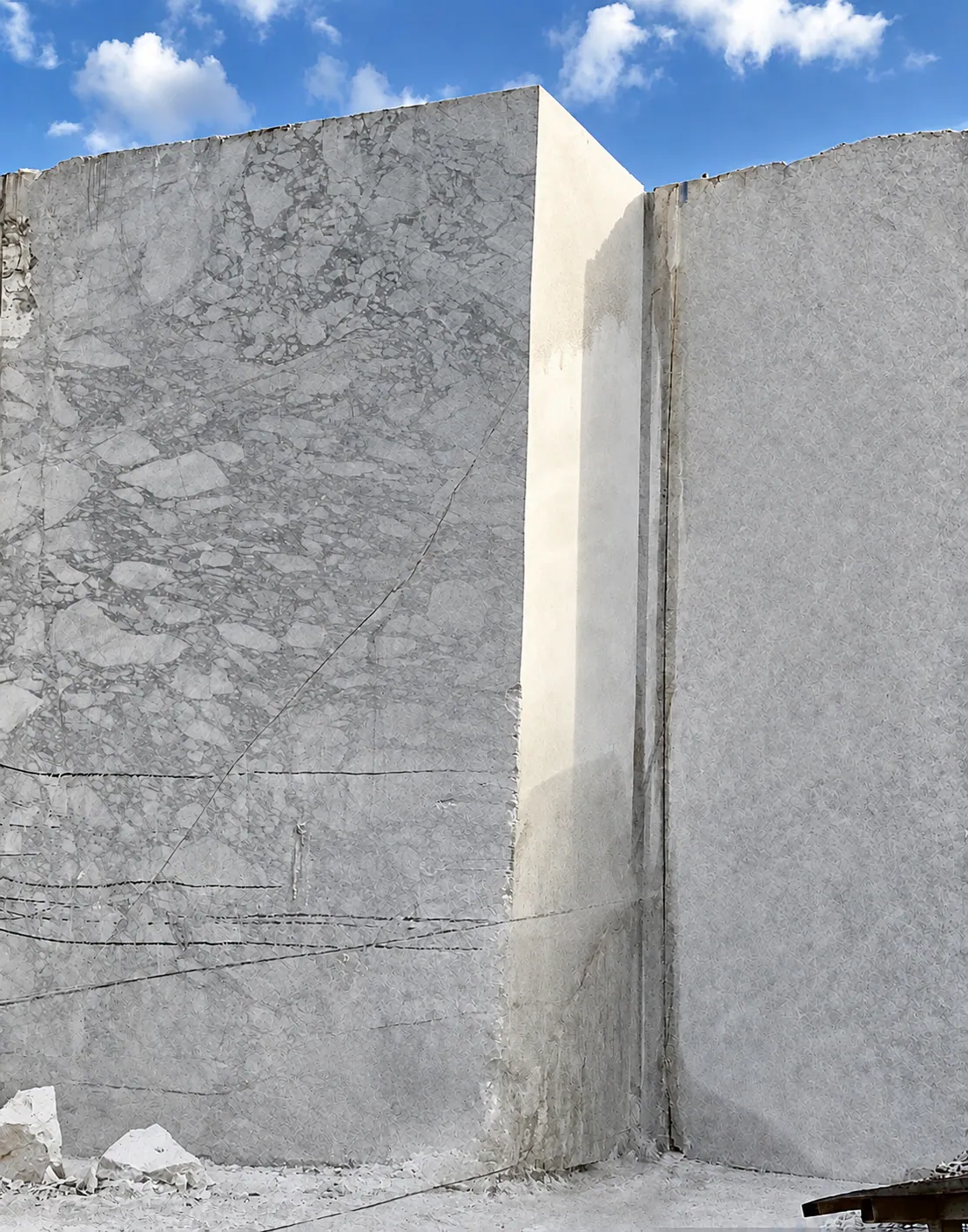 Photograph: sawn white stone faces of a quarry bench, marked by wire-saw lines.